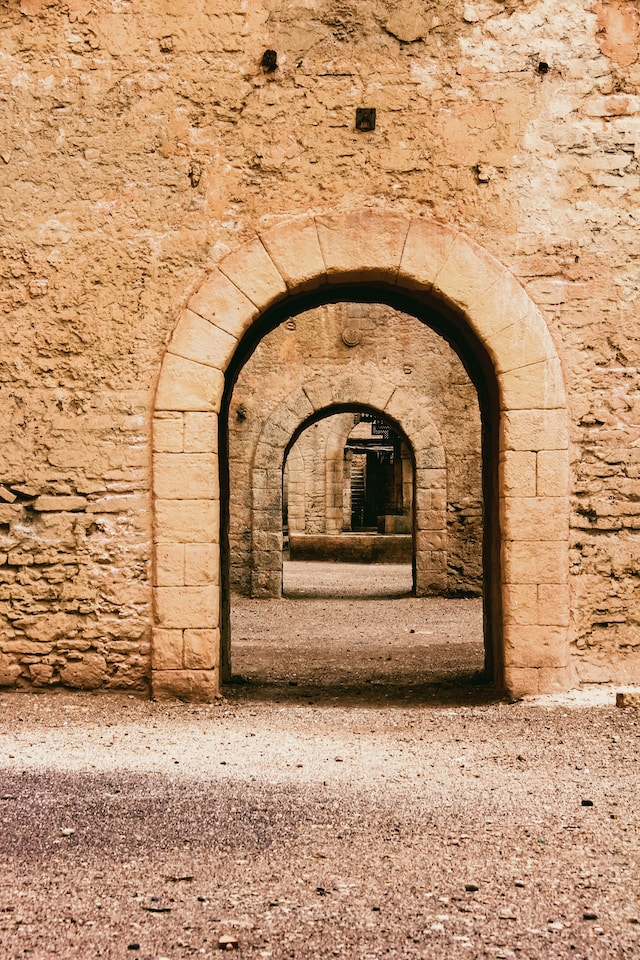 Vue d'une arche ouverte dans un ancien mur en pierre. Au travers de cette arche, on en voit une autre de la même forme, et ce récursivement.